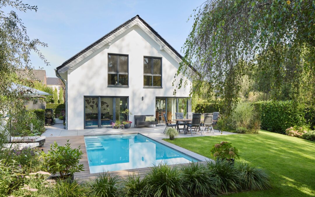 Ein moderner Familiengarten am Niederrhein mit Pool, Terrasse aus Holz und Rasenfläche verbindet klare Architektur mit individueller Gartengestaltung.